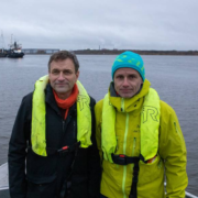 Arild Hermstad og Erik Skauen står på dekket til en båt med sjø i bakgrunnen.