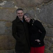 En mann og en kvinne står inntil hverandre og ler. Kvinnen lener seg på mannen.